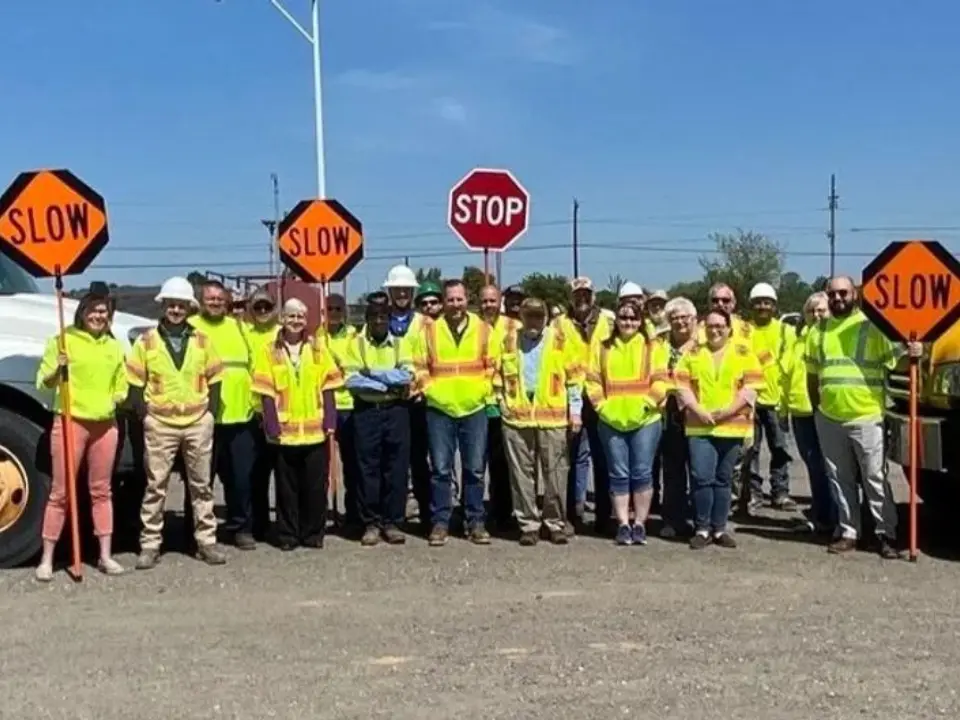 A crew of David A Bramble employees carrying stop and slow signs together in yellow vests