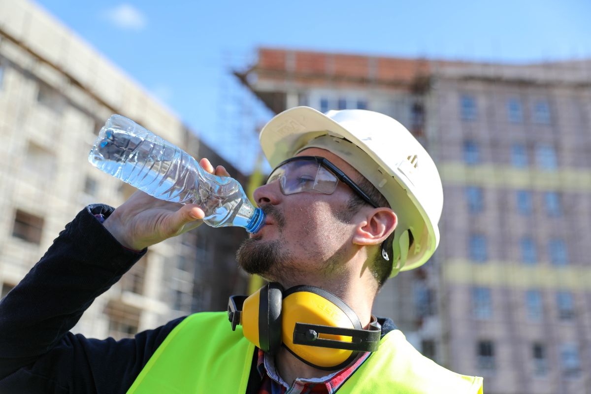 iStock Stock Image of a Construction Worker drinking bottled water in the heat with buildings in the background